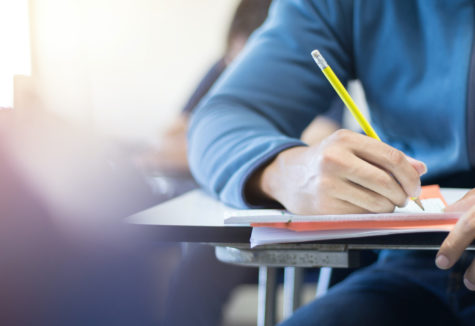 A student taking a test at a classroom desk.