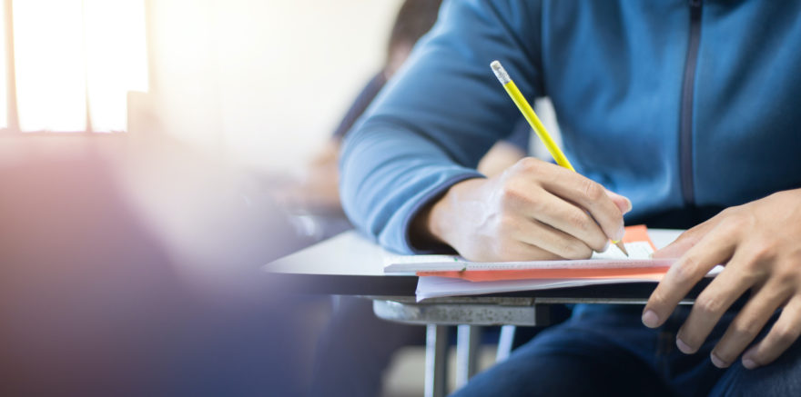 A student taking a test at a classroom desk.