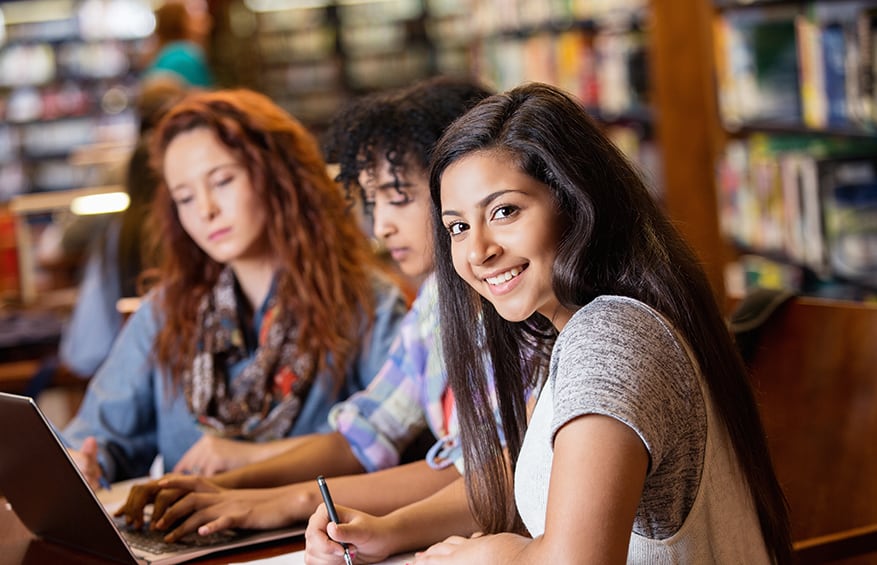 three high-school girls studying in their school library.