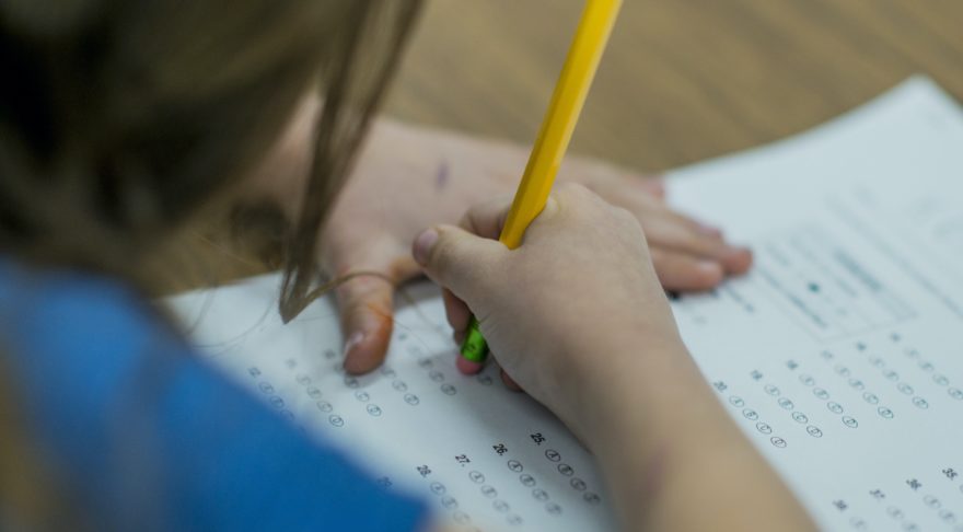 A young student erasing an answer from a standardized testing answer sheet.