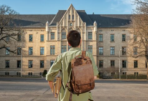 One student walking toward the front of the school.