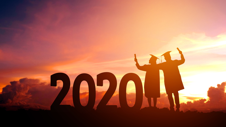 Two graduates next to large numbers saying '2020' backlit by a fiery sunset.