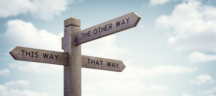 A wooden signpost that mark 'This Way', 'That Way', and 'The Other Way'.