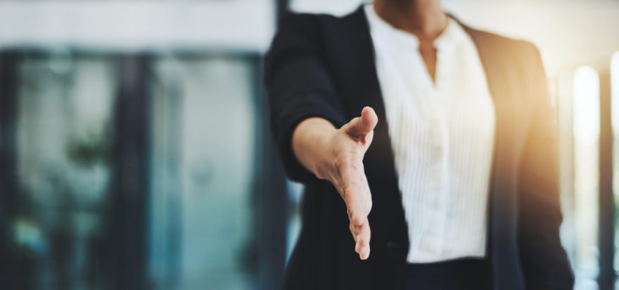 A professional businesswoman extending her hand.