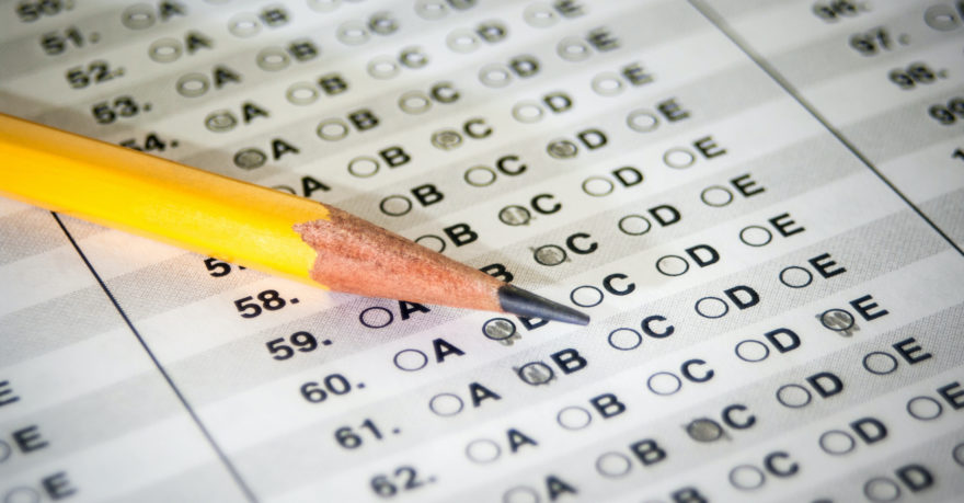 A closeup image of a pencil laying on a multiple-choice answer form.