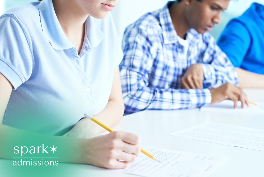 Students taking a standardized test in a classroom while completing exam papers with pencils.