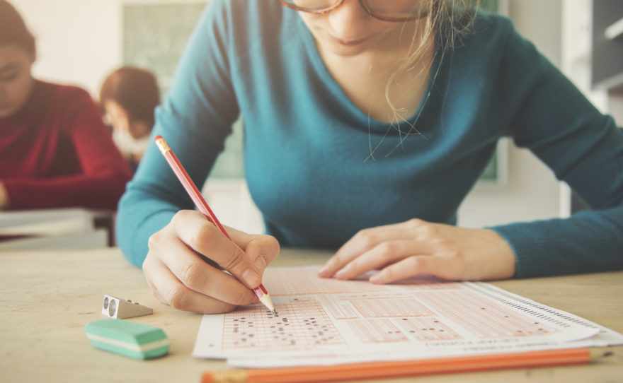 A female student at her school desk taking a test on a scantron form.