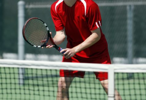 A man playing tennis up close to the net.