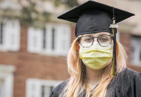 A 2020 graduate in her cap and gown wearing a yellow protective face mask.