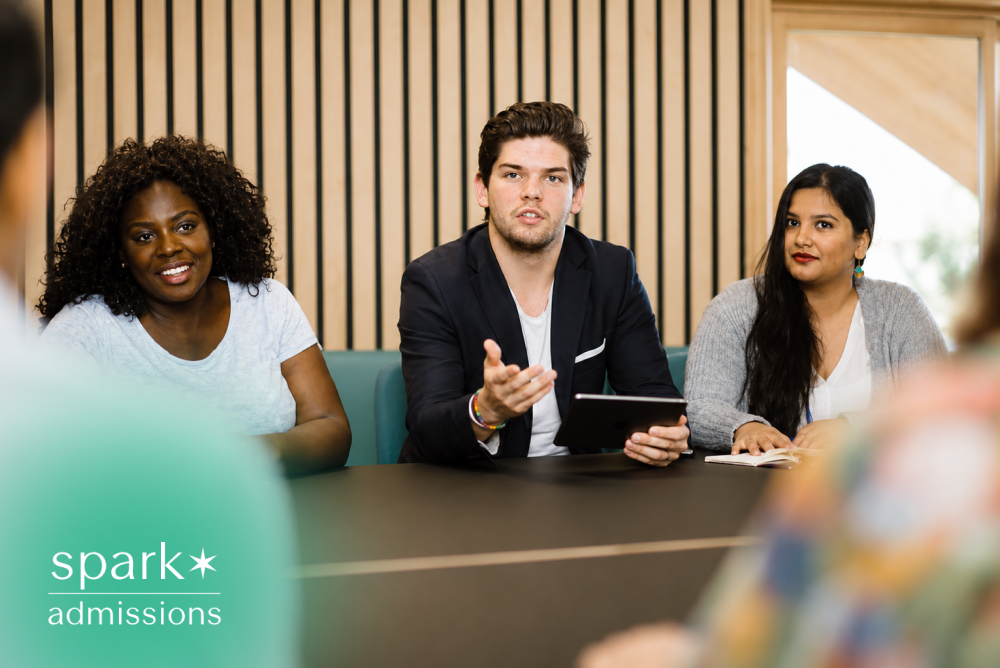 Diverse college students participating in a group discussion, with one student presenting ideas during a collaborative classroom meeting.