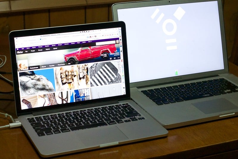 Two Macbook Pro laptops on a desk transferring data from one to the other.