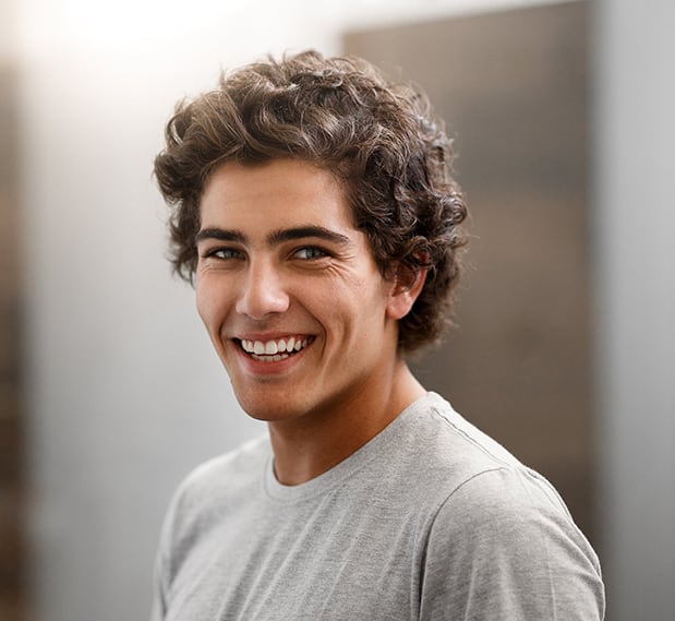 Smiling male college student of multiethnic descent with short, curly brown hair