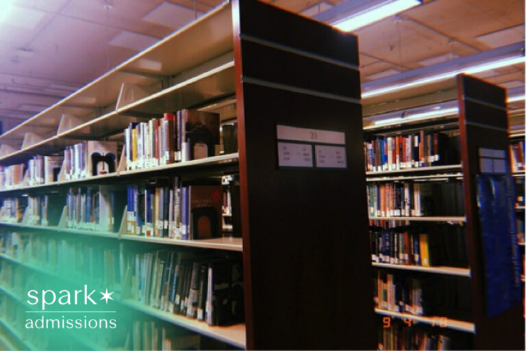 Rows of bookshelves filled with academic books and study resources inside a quiet college library.