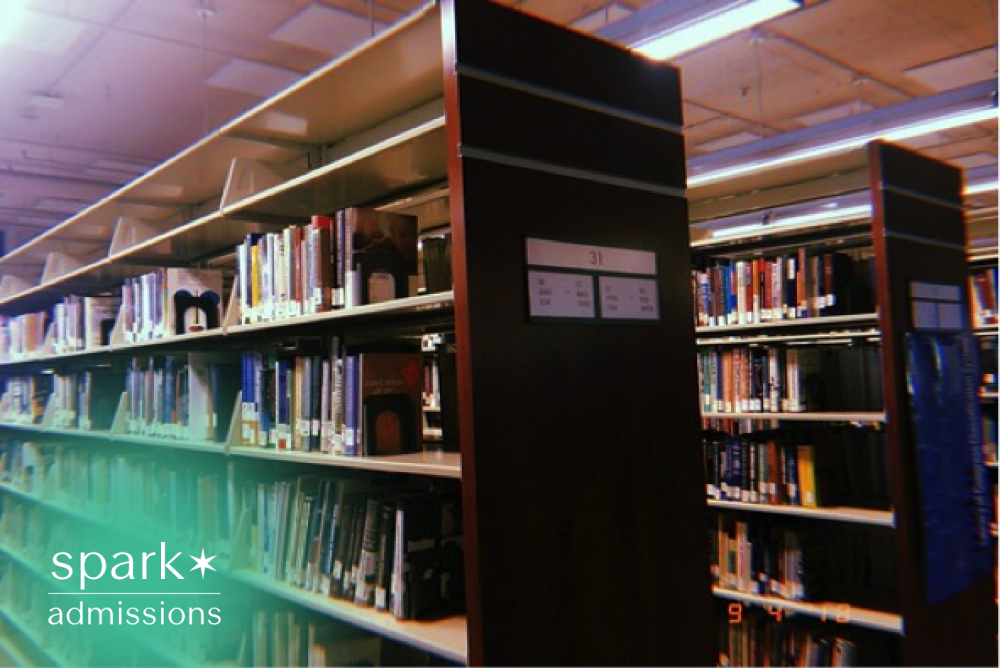 Rows of bookshelves filled with academic books and study resources inside a quiet college library.