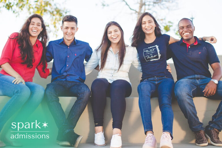 Diverse group of smiling college students sitting together outdoors on campus, showing friendship, inclusion, and student life.