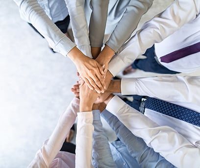 A team putting their hands together in a stack in a show of team spirit.