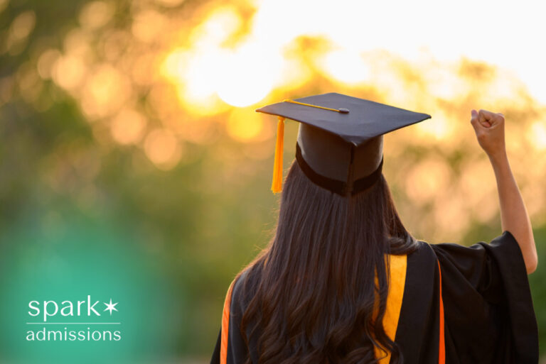 Graduate celebrating college graduation at sunset while wearing a cap and gown.