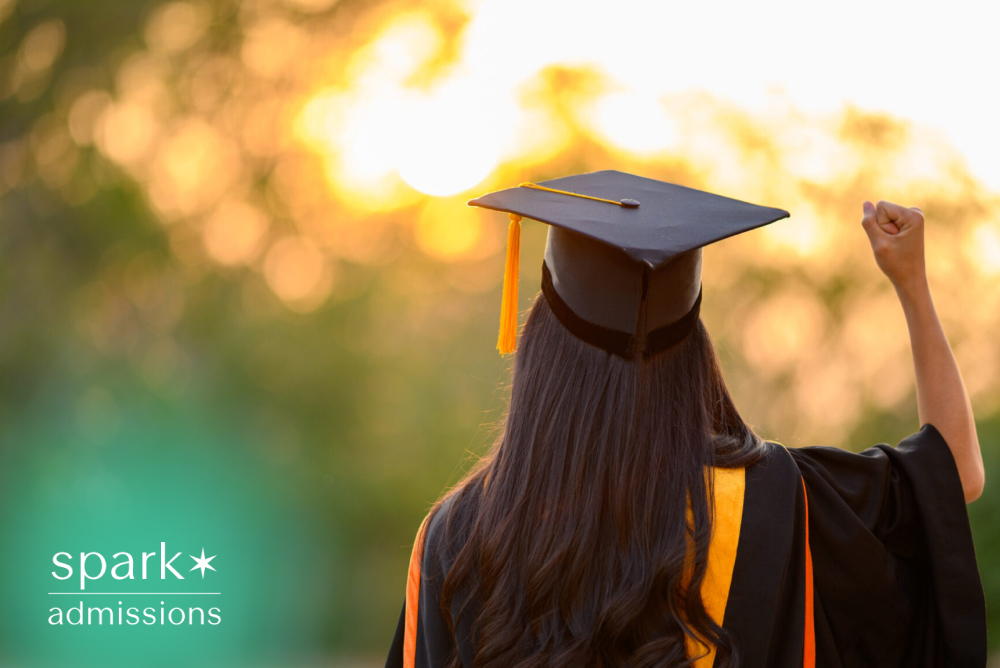 Graduate celebrating college graduation at sunset while wearing a cap and gown.