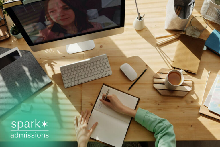Student taking notes during an online class at a home desk with a computer and notebook.