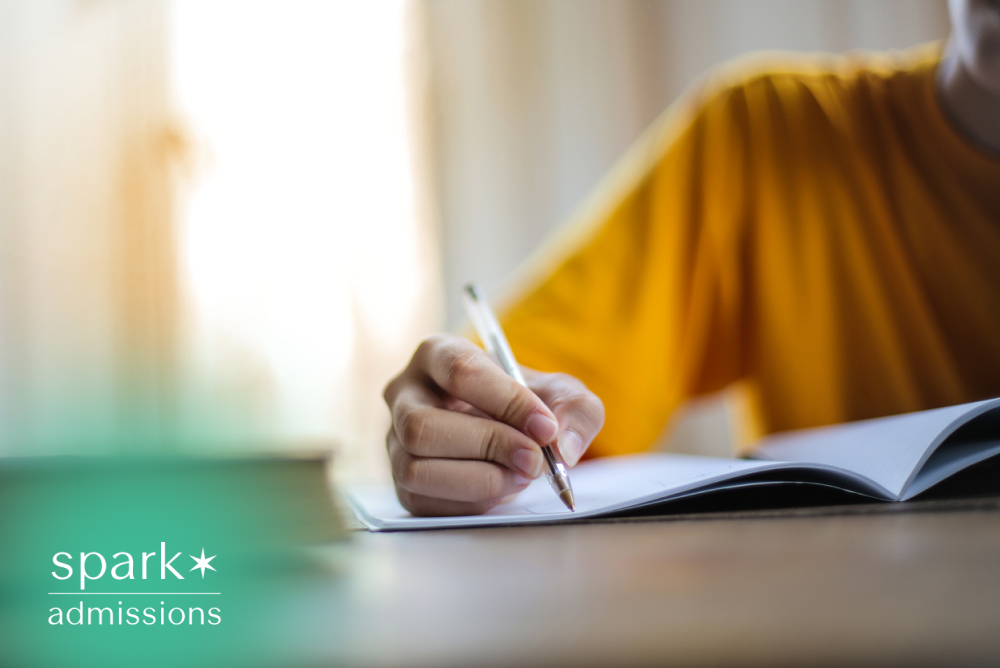 Student writing study notes in a notebook during a focused study session