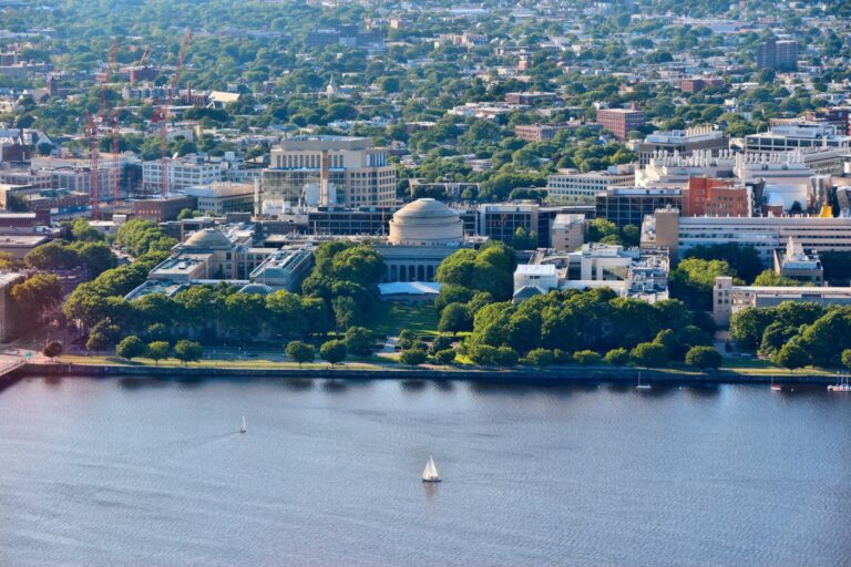 An aerial view of the MIT campus in Cambridge shows domed buildings along the river