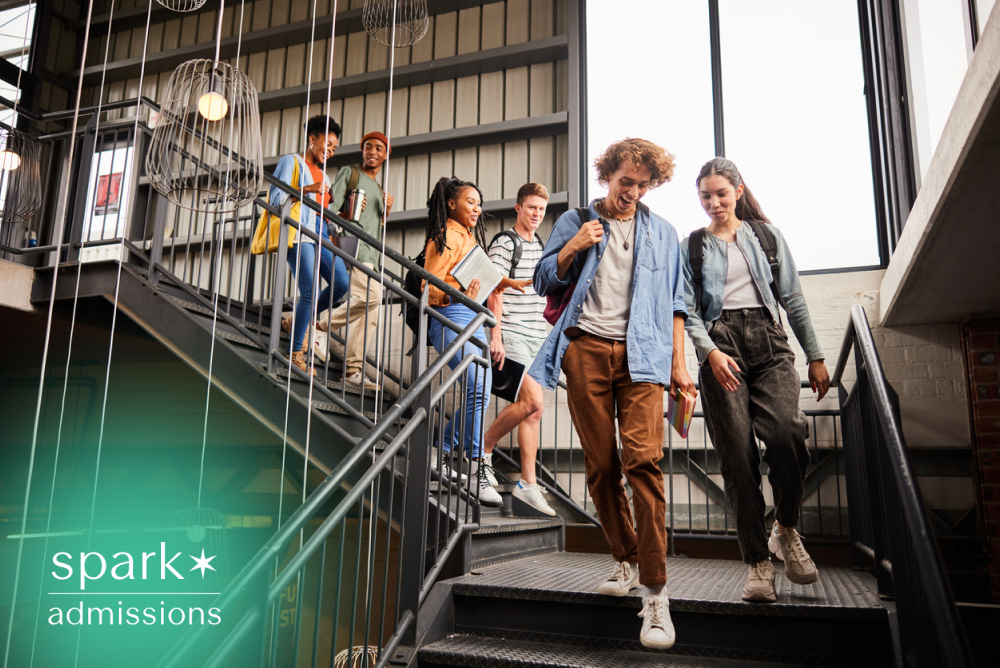 Diverse group of college students walking down a modern campus staircase between classes, carrying backpacks and books while socializing in a bright university building.