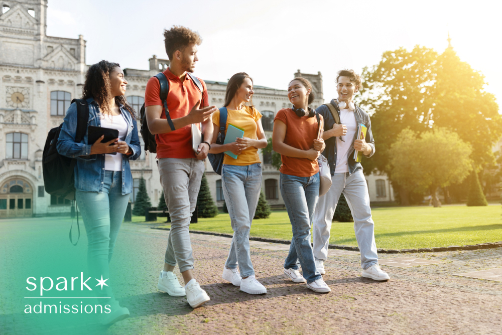 Diverse group of college students walking across a university campus together, carrying backpacks and notebooks while talking and smiling on a sunny day.