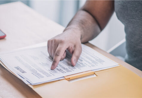 Close-up of a hand pointing at a document on a desk