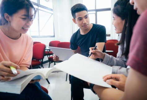 Group of college students gathered indoors having a conversation in a classroom or study lounge
