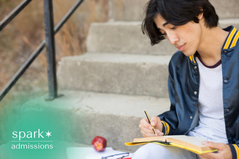 Student writing notes in a notebook while sitting on campus steps