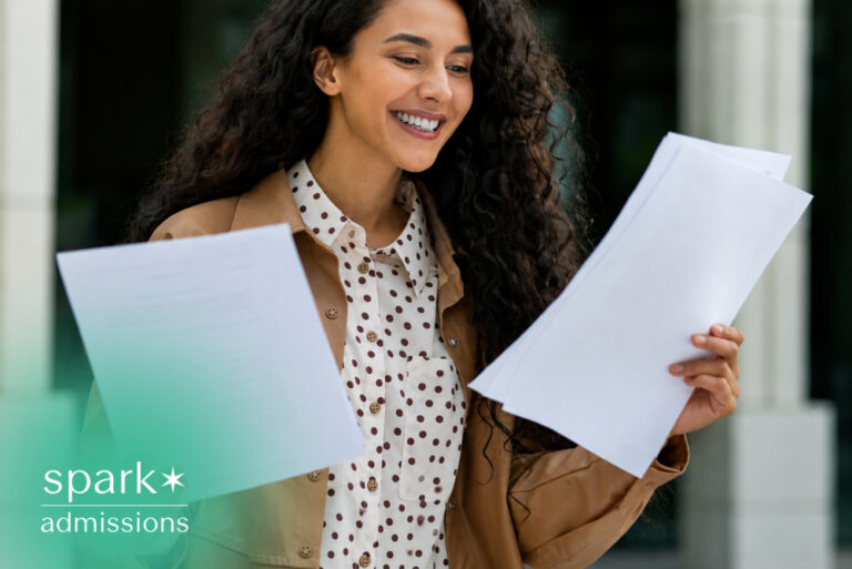 Student smiling while holding admissions application papers