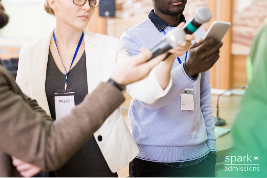 Reporters hold out microphones and smartphones during a press interview for Political Science Major