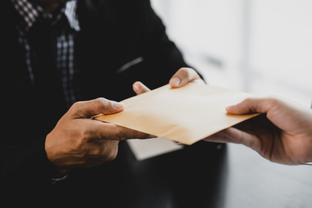 A person hands over a sealed envelope to another person