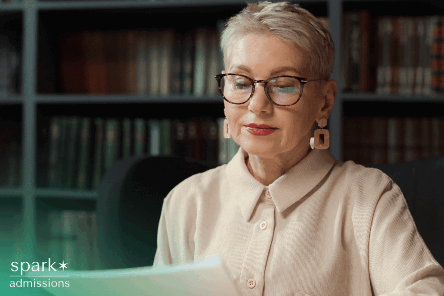 Female college admissions officer looking over student application paperwork at her desk
