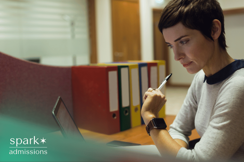 Female admissions officer reviewing college applications on laptop
