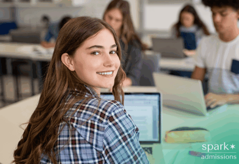 Smiling female student using laptop to complete Common App for college