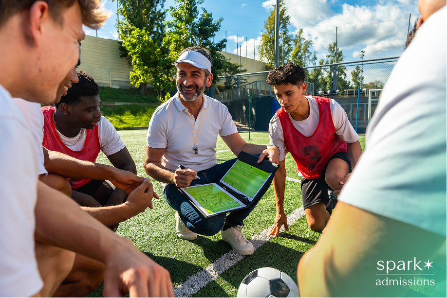 High school athletes reviewing plays with their coach, illustrating how sports involvement strengthens college applications.