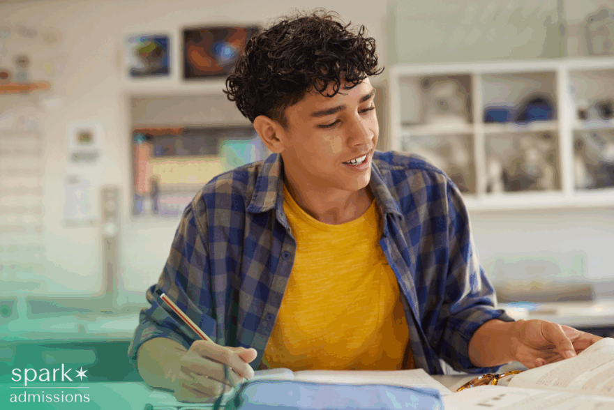 Male high school student studying and reading a book