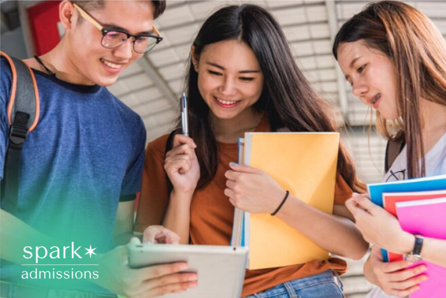 Students reviewing college application details together on a tablet