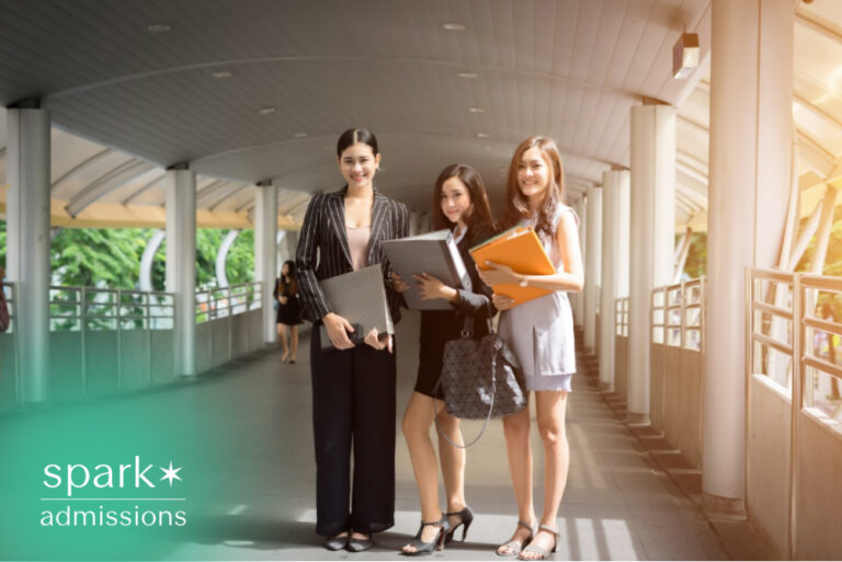 Three female business students carrying folders on a university campus.