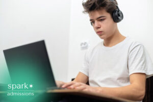 High school student wearing headphones while studying online on a laptop.