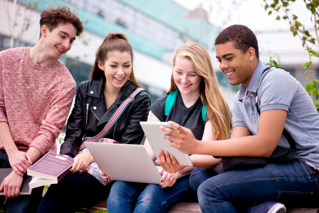Group of college students using a laptop and tablet during strategic college planning and admissions preparation.