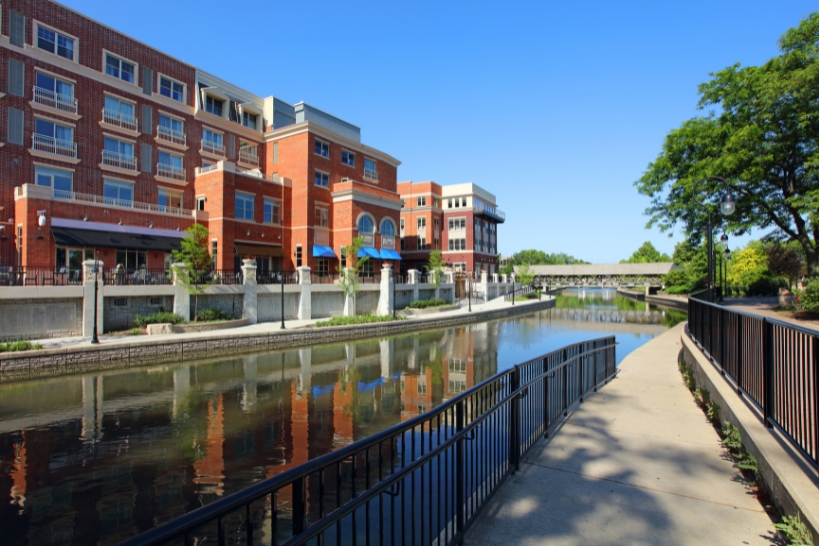 Scenic view of the Naperville Riverwalk and downtown buildings in Naperville, IL.